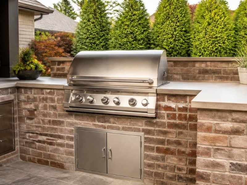 Outdoor kitchen with a built-in grill and access panel in the brick masonry wall in Frisco, Texas.