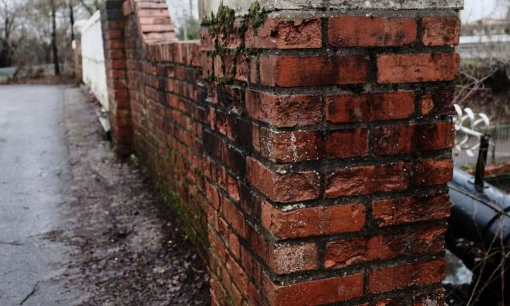 Brick masonry wall topped with an overhanging cap that helps protect the wall from rainwater